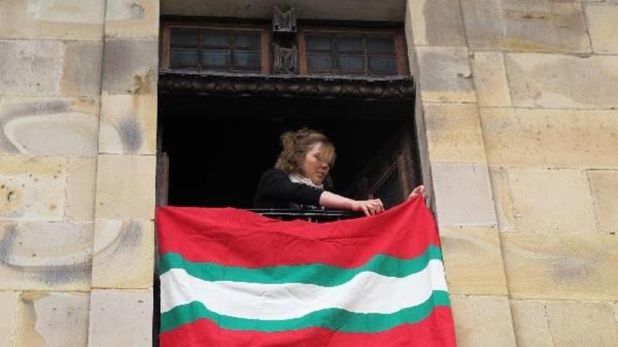 La técnico de Cultura de Segura, colocando una ikurriña en uno de los balcones del ayuntamiento.