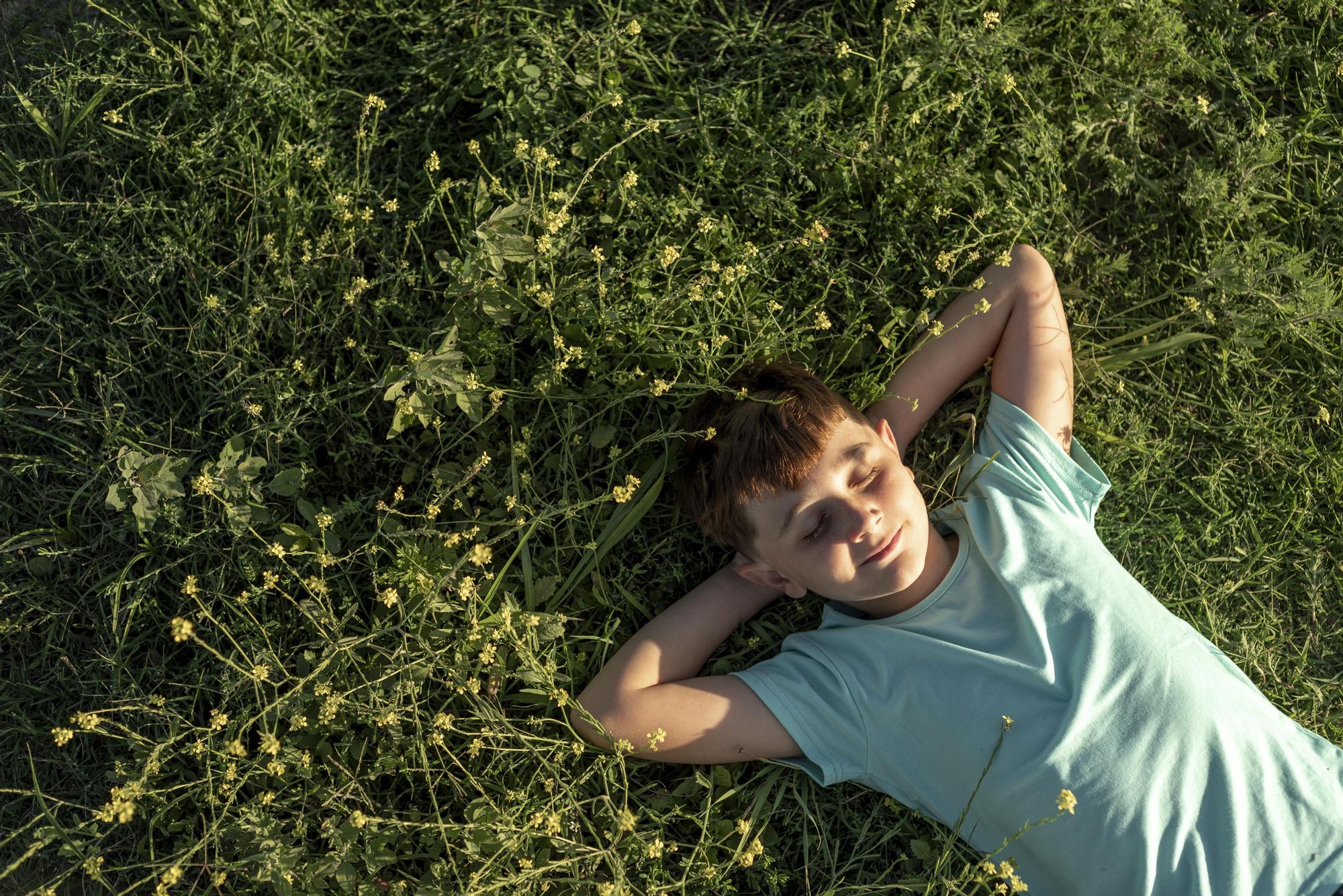 Un niño se relaja tumbado en la hierba.