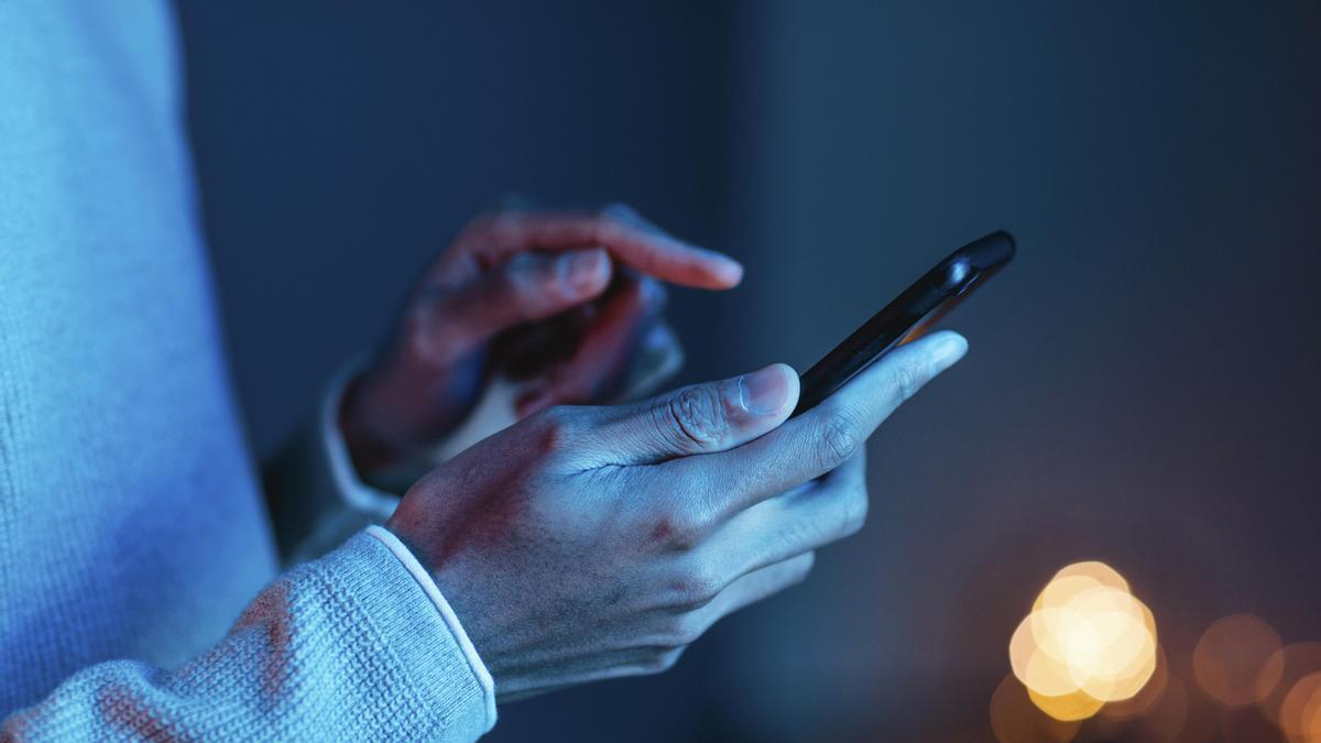 Un hombre consulta su teléfono móvil.