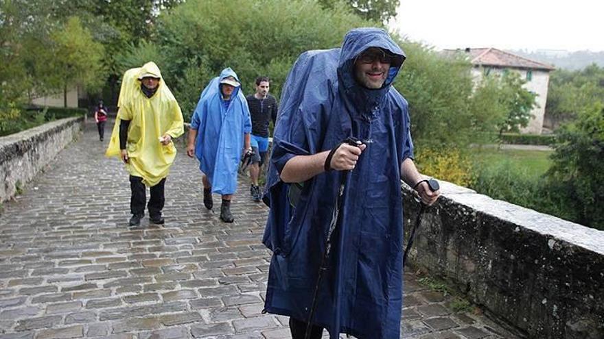 Peregrinos protegiéndose de la lluvia con chubasqueros.