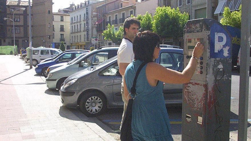 Una mujer extrae un ticket para estacionar en la zona azul de la calle Muro.