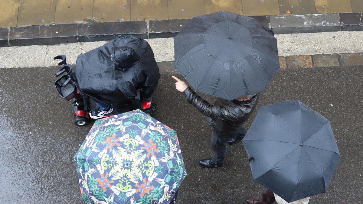 Personas paseando por Pamplona durante un día lluvioso.
