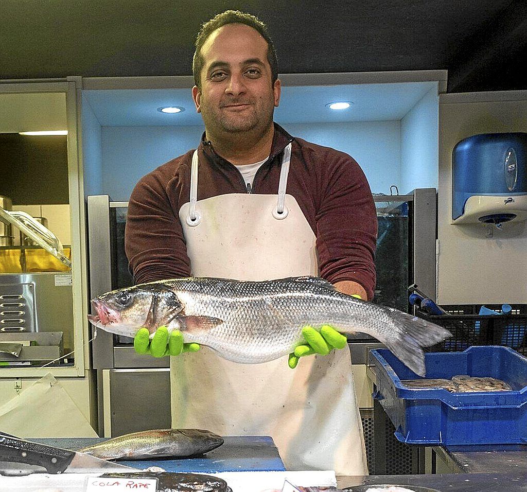 Issam muestra una lubina en su puesto de Abastos.