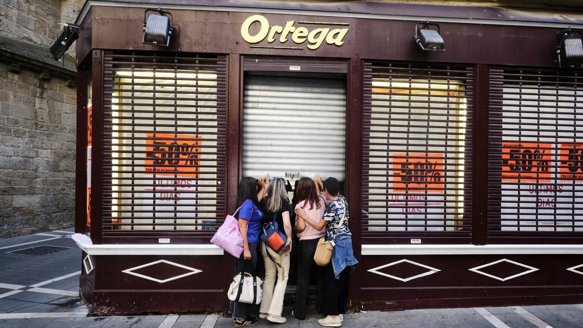 Trabajadoras de Ortega bajan la persiana el último día de de la tienda.
