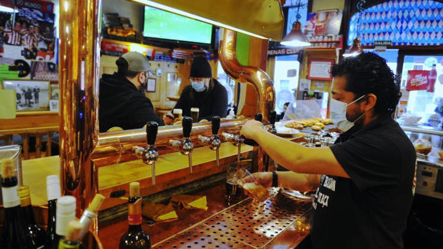 El responsable de un bar sirve a unos clientes.