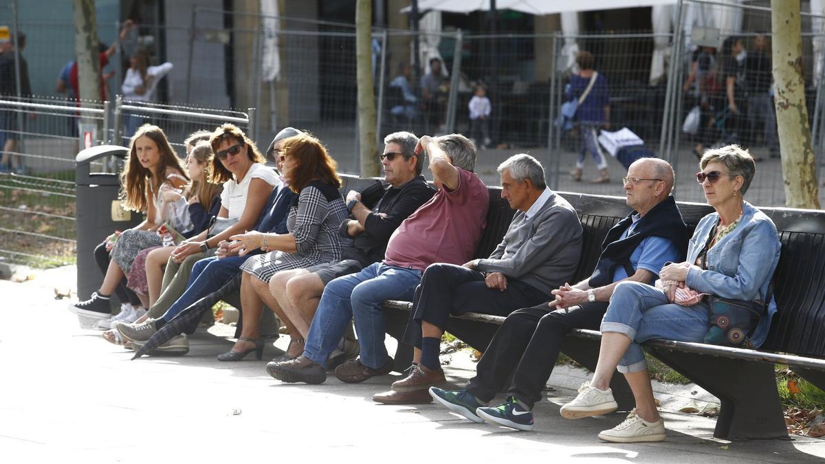 Gente descansando en un banco de la Plaza del Castillo.