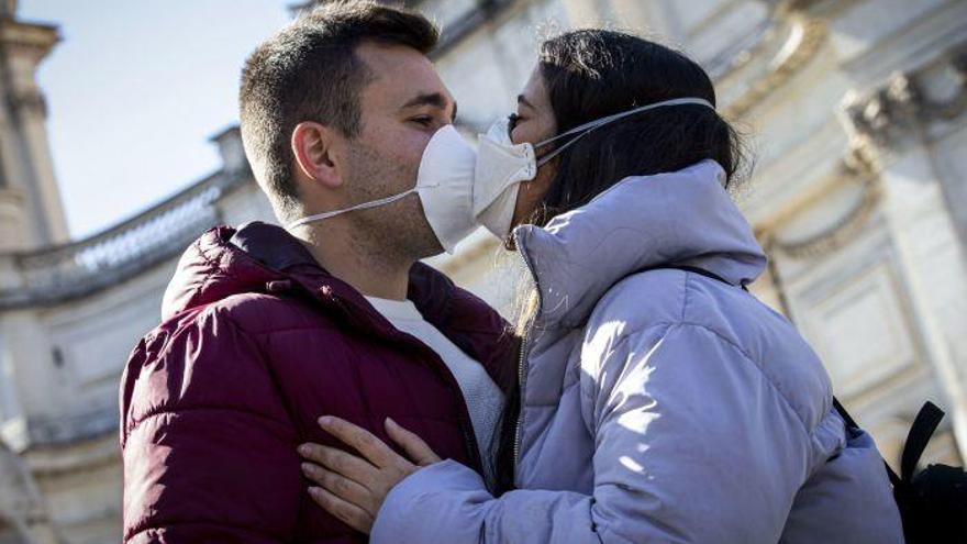 Una pareja protegida con mascarillas se da un beso, ayer, en Roma.