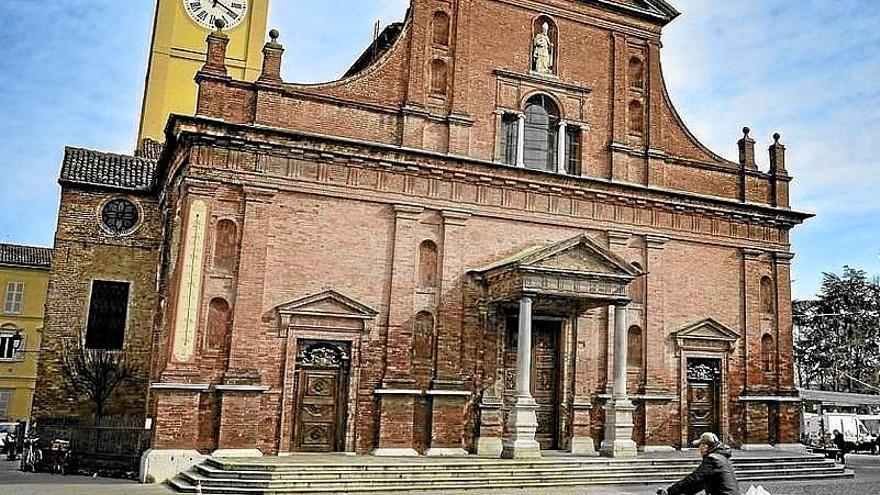 Un hombre pasea en bicicleta frente a la iglesia de Codogno.