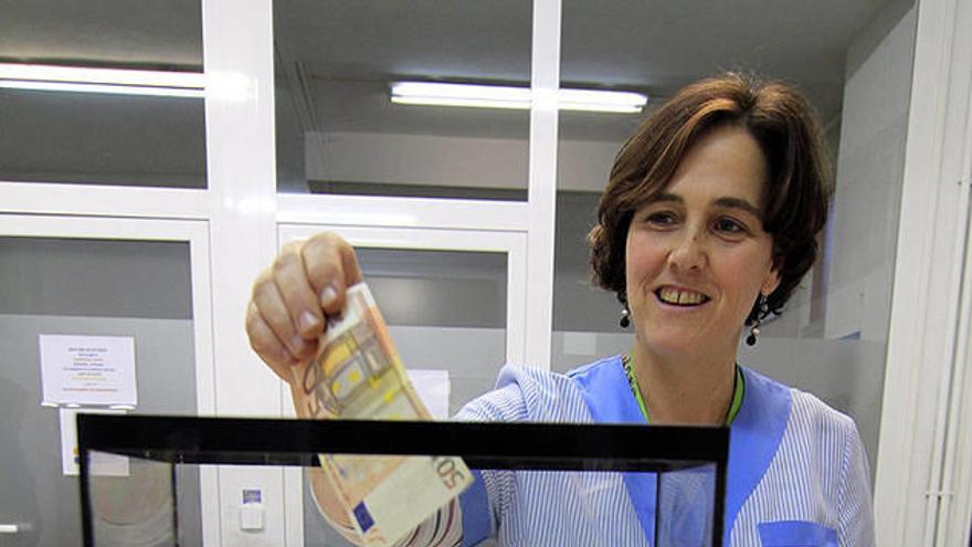 La maestra Andion Iriarte mete su dinero en la hucha.