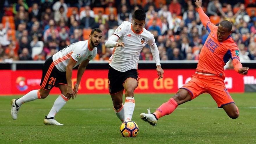 El defensa portugués del Valencia João Cancelo (c) disputa un balón con entre el defensa brasileño Gabriel Silva (d), del Granada, durante el partido de la duodécima jornada de la Liga de Primera División jugado hoy en el estadio de Mestalla