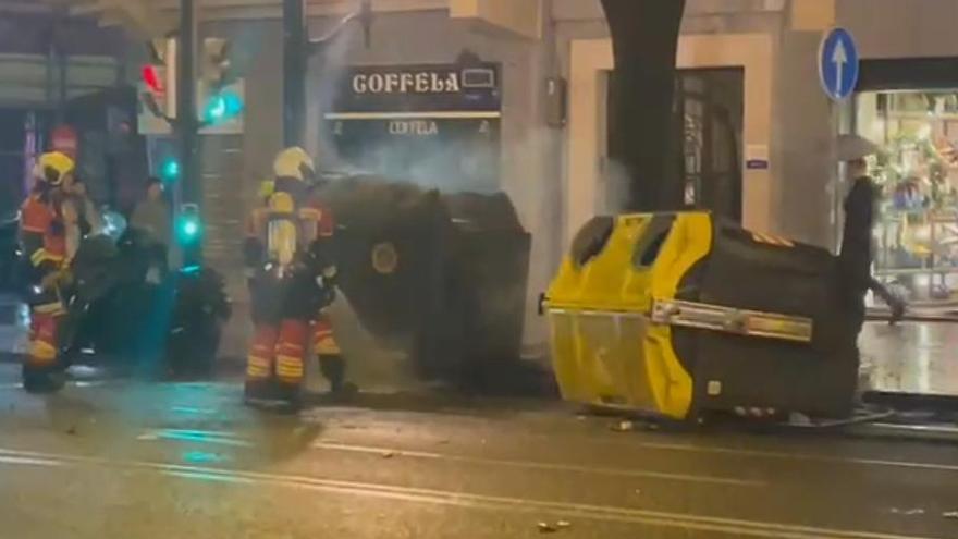 Bomberos apagan las llamas ocasionadas por el lanzamiento de bengalas a unos contenedores