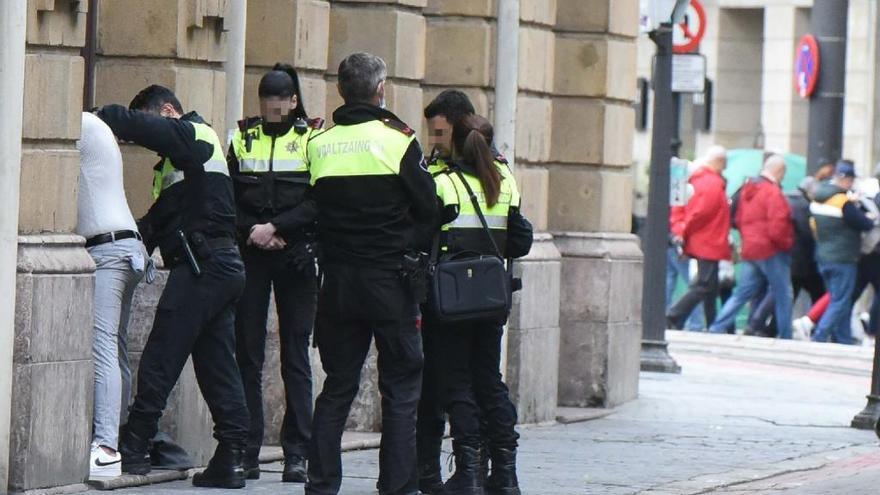 Un agente cachea a un presunto delincuente ante varios compañeros de patrulla.