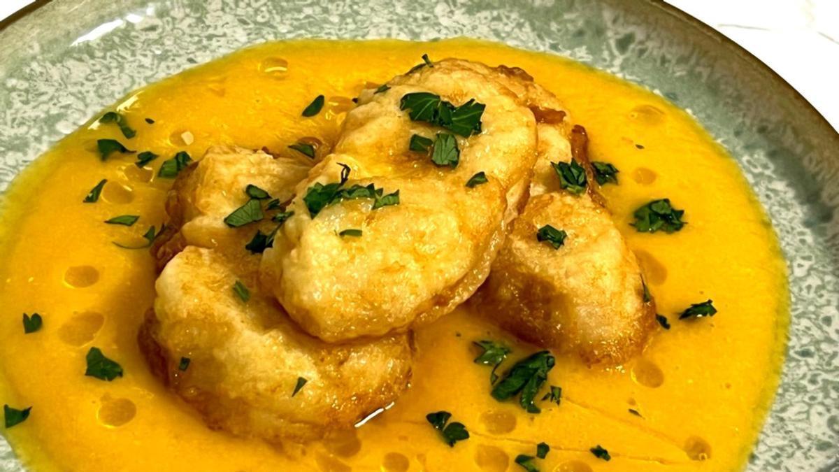 Medallones de merluza sobre una crema de calabaza y langostinos.