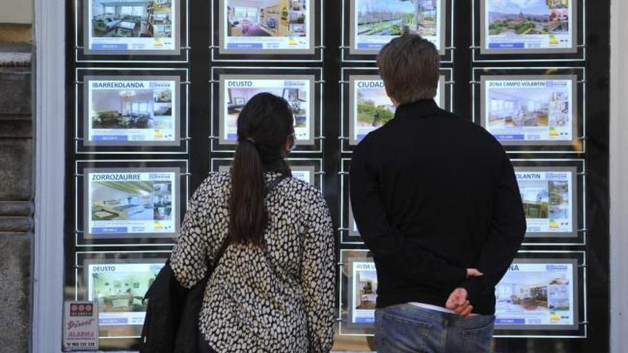 Jóvenes observan pisos en una inmobiliaria.