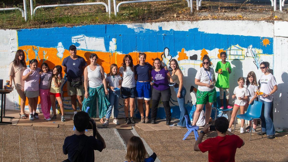 Txikis y educadoras posan junto al mural durante la elaboración.