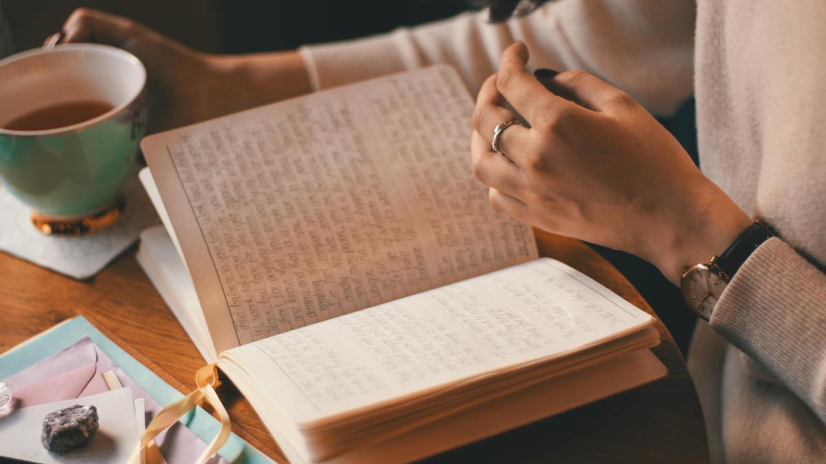 Una persona tomando café con un cuaderno en frente.