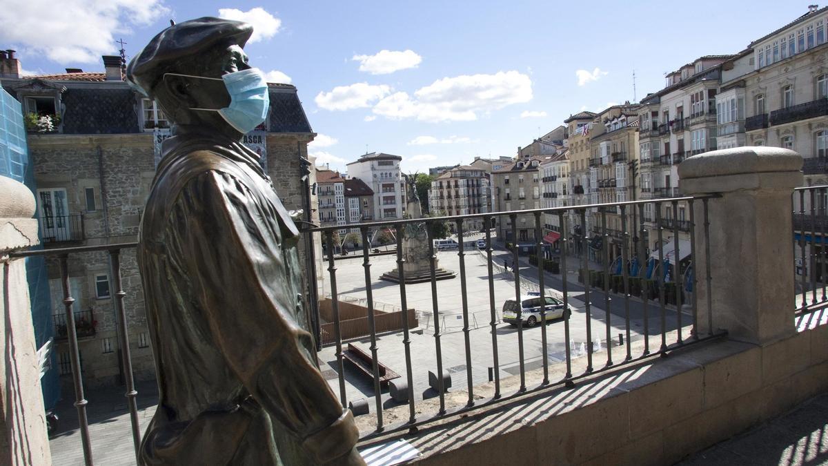 La estatua de Celedón ataviada con una mascarilla y la plaza de la Virgen Blanca vallada para impedir el acceso con motivo de la suspensión de las fiestas por la pandemia en 2020