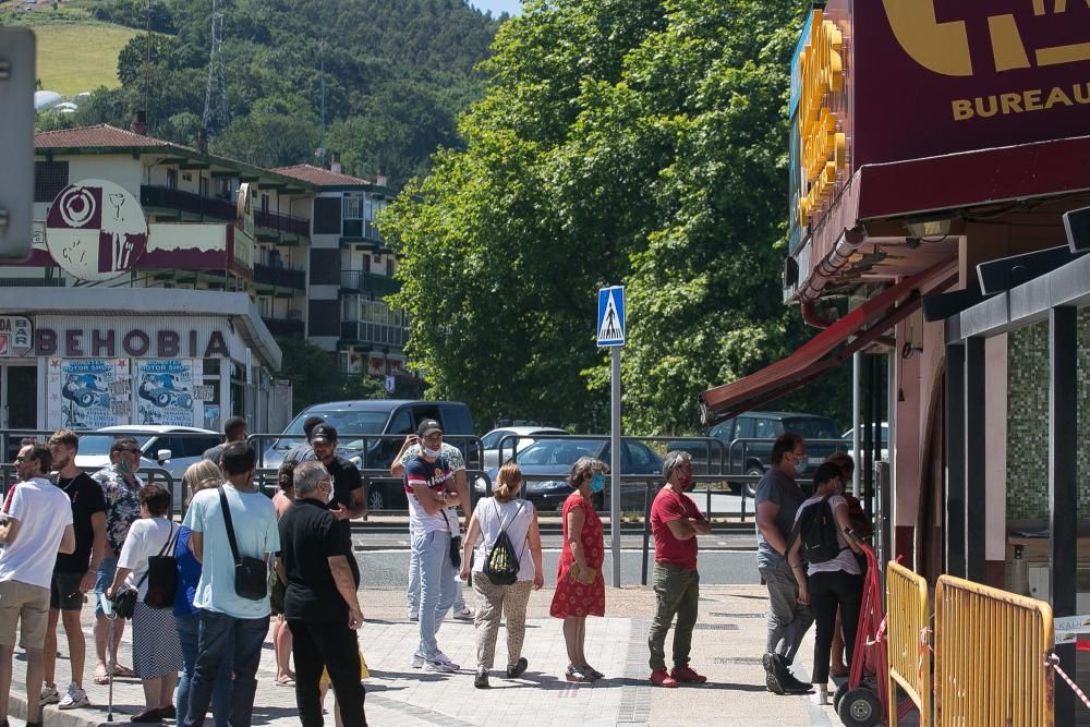 Varias personas hacen cola ante un estanco de Behobia este domingo.