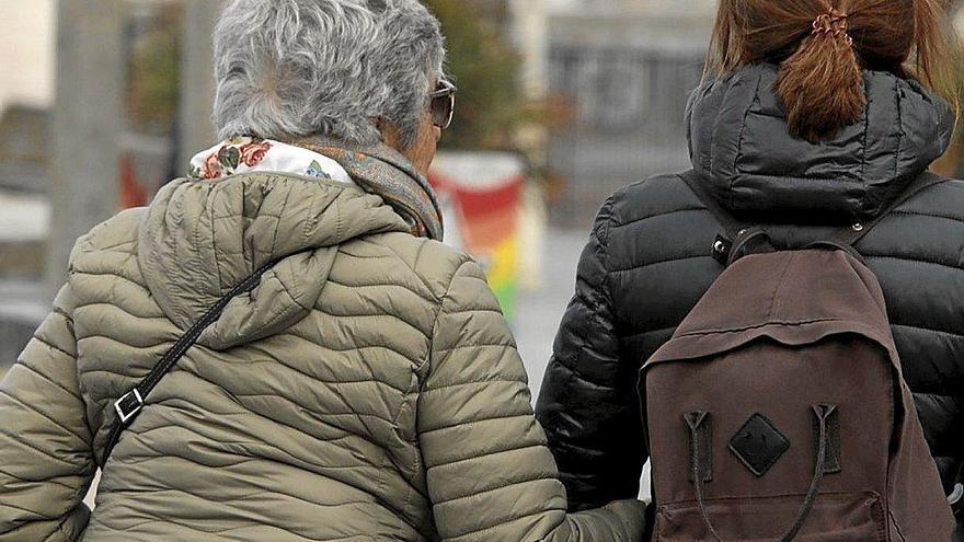 Una mujer mayor pasea del brazo de una joven.