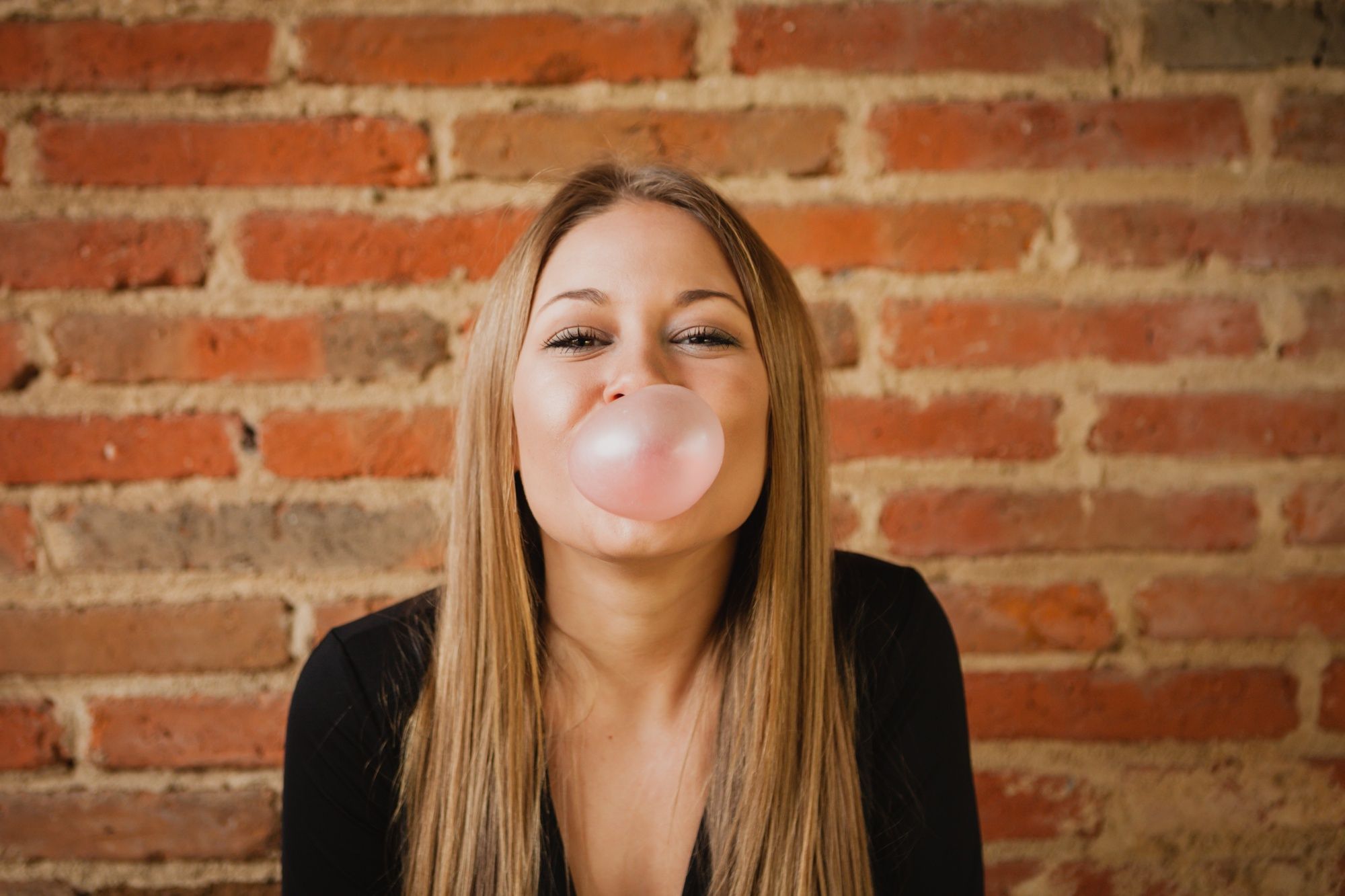 Una joven hace una pompa de chicle.