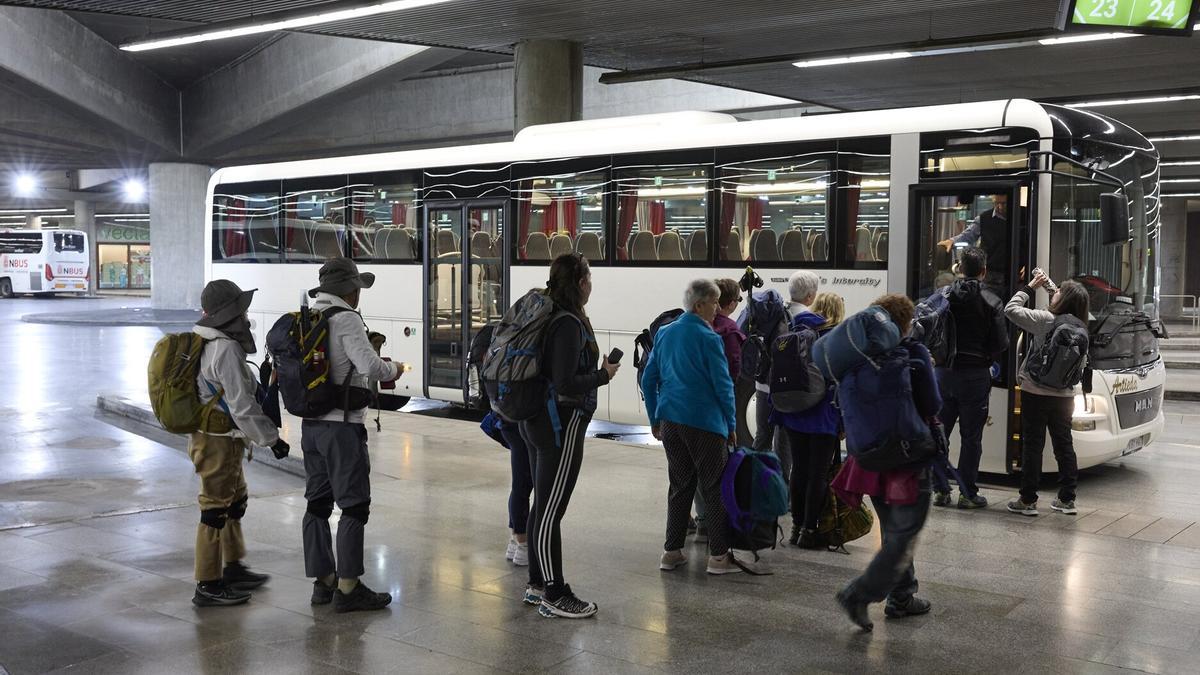 Un grupo de personas hace fila para subir a un autobús en la estación de Pamplona.