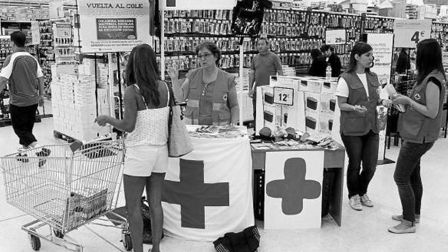 Una joven se informa de la recogida de material escolar para menores en riesgo de exclusión social.