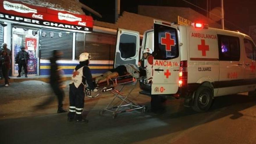 Paramédicos de la Cruz Roja trasladan ho a una persona herida en la zona donde un grupo de sicarios irrumpió con armas largas en un bar de Ciudad Juárez