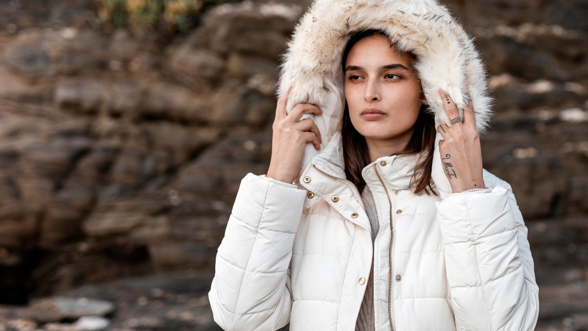 Una mujer se abriga con un plumífero en un día frío de invierno.