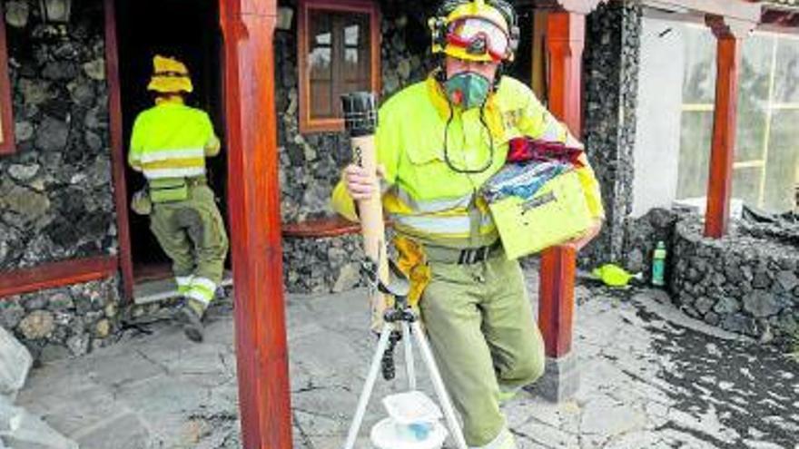 Bomberos sacan enseres de una casa a punto de ser alcanzada por la lava. Foto Europa Press