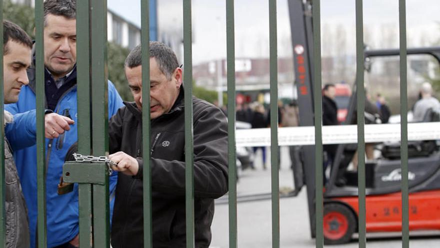 Tres trabajadores tratan de cerrar las puertas de la fábrica para evitar que salgan los directivos hasta que no ofrezcan una solución.