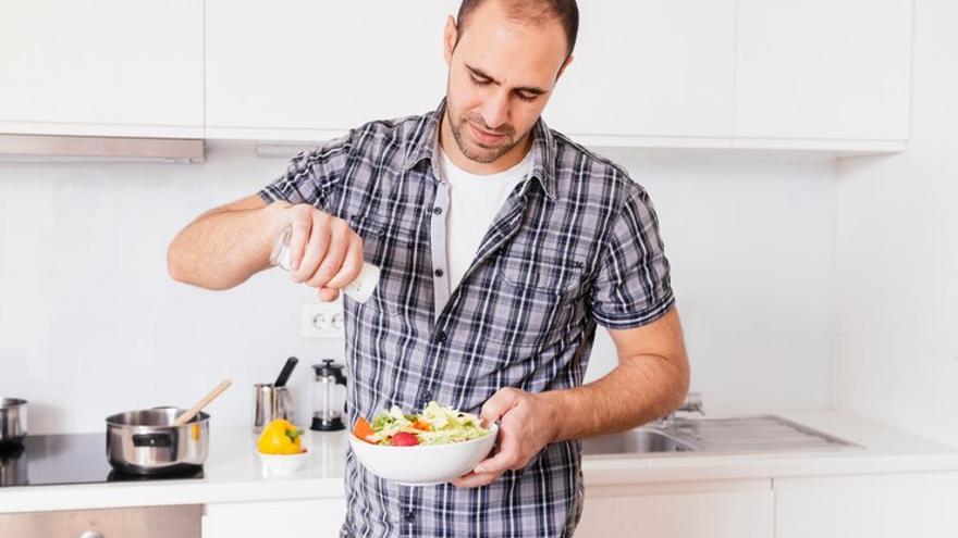 Hombre condimentando una ensalada.