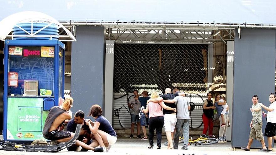 Varios jóvenes permanecen junto a los restos de un vehículo, en el lugar del atropello masivo de una furgoneta que ha arrollado esta tarde a varias personas que paseaban por las Ramblas de Barcelona