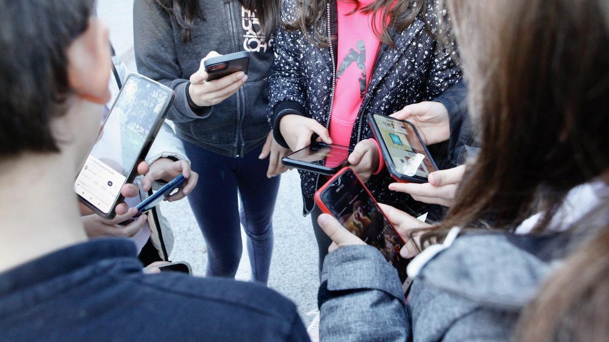 Jóvenes utilizando sus teléfonos móviles.
