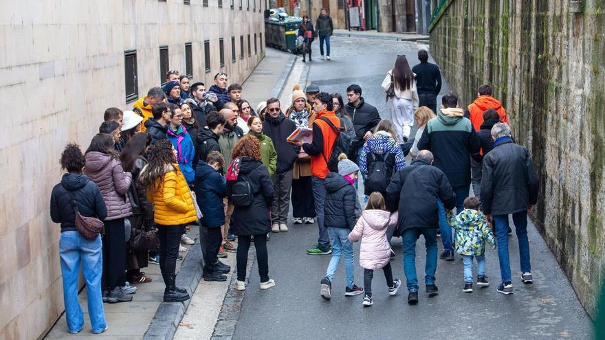 Una veintena de personas escuchan las explicaciones del guía durante su visita guiada mientras recorren el Casco Viejo de Pamplona.