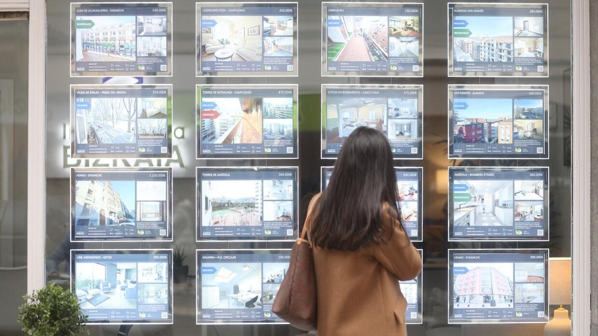 Una mujer mira los precios de los pisos en una inmobiliaria de Bilbao