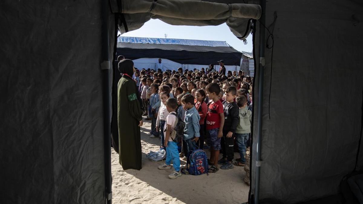 Niños palestinos hacen fila en una escuela de campaña establecida por UNICEF en el campo de refugiados de Khan Yunis