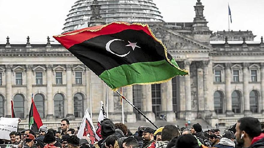 Las personas ondean la bandera libia en una protesta contra el hombre fuerte libio Khalifa Haftar durante la conferencia de Berlín.