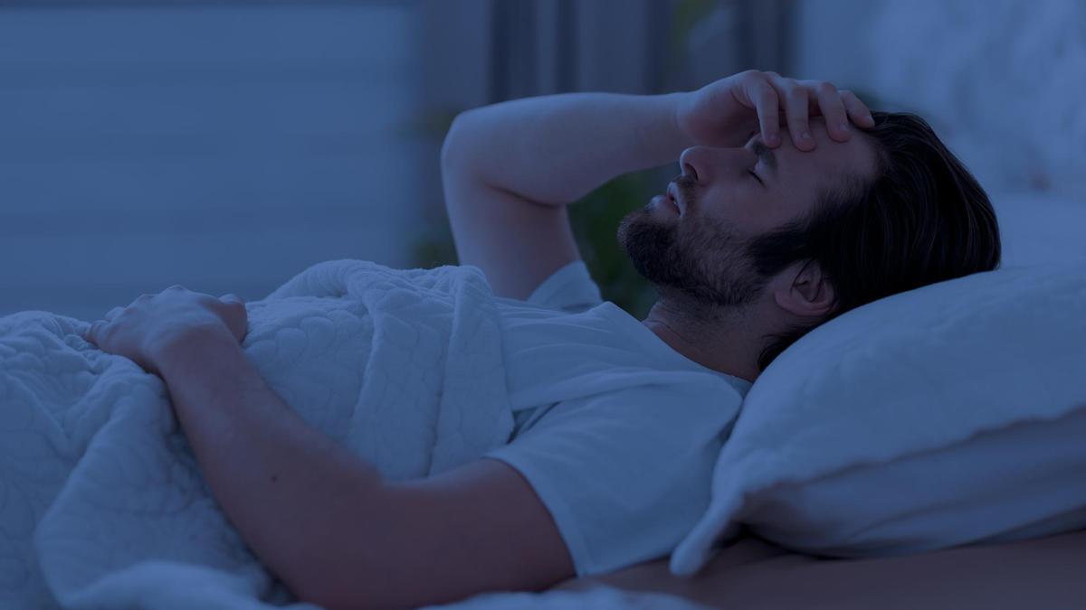Un hombre tumbado en la cama sin poder conciliar el sueño