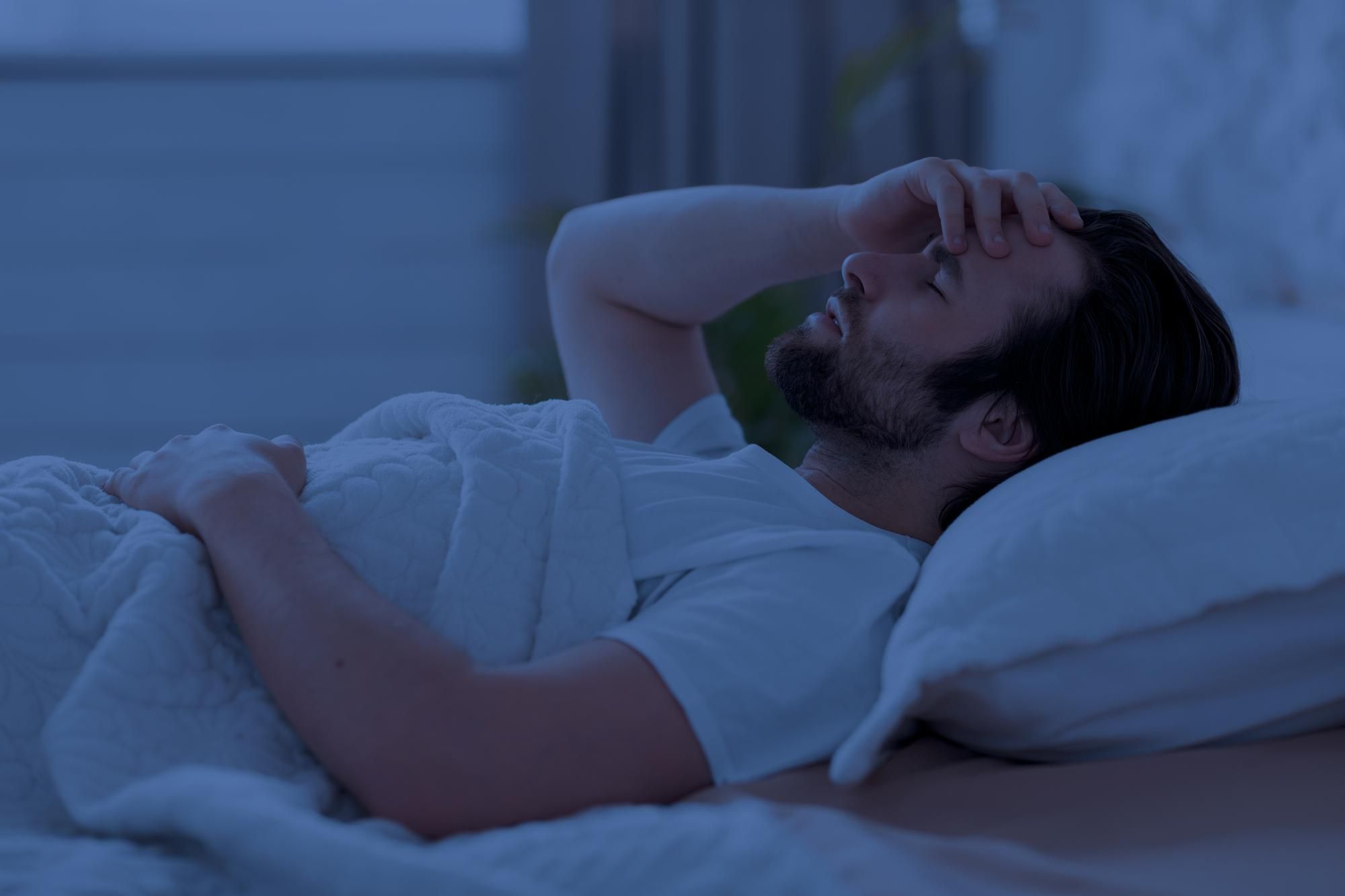 Un hombre tumbado en la cama sin poder conciliar el sueño.