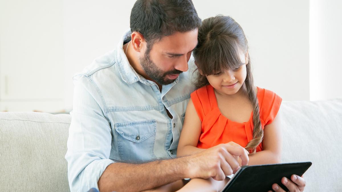 Un padre y su hija  comparten tiempo y tablet.