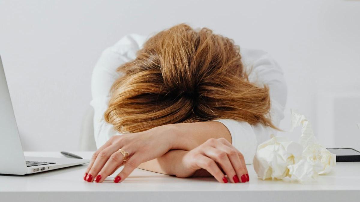 Una mujer con la cabeza sobre su escritorio.