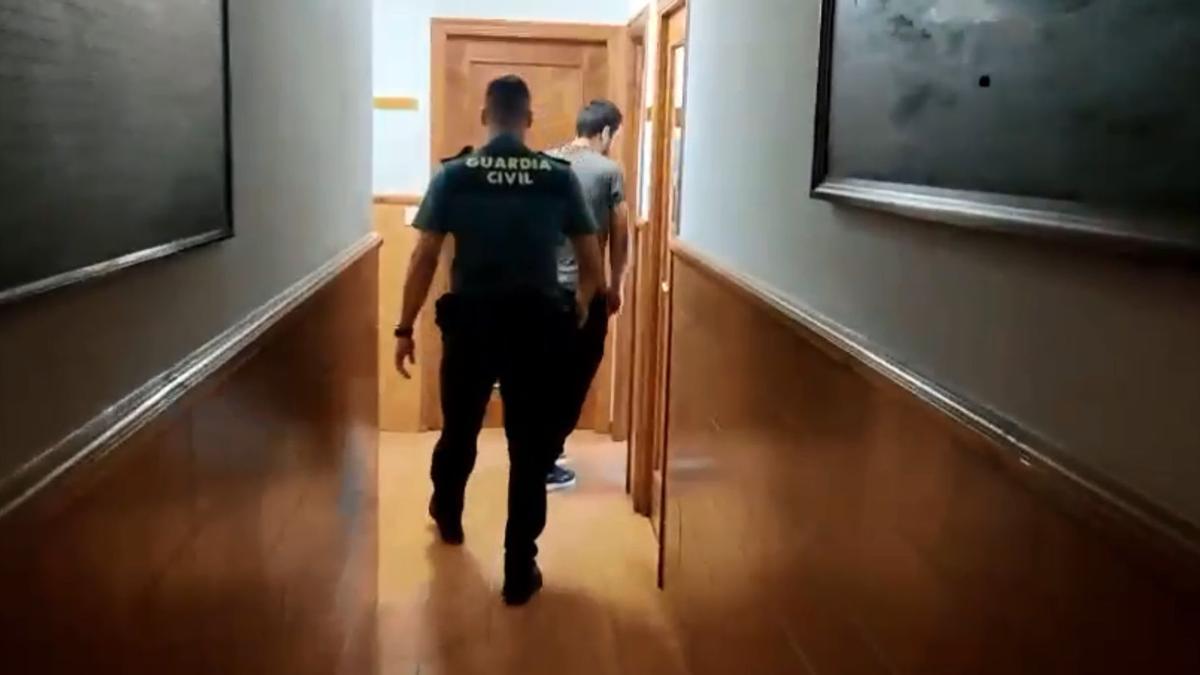 Un agente acompaña a uno de los imputados a tomar declaración.