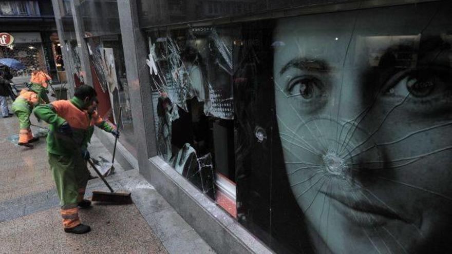 Operarios limpian los destrozos en uan sucrusal de la BBK en el Casco Viejo