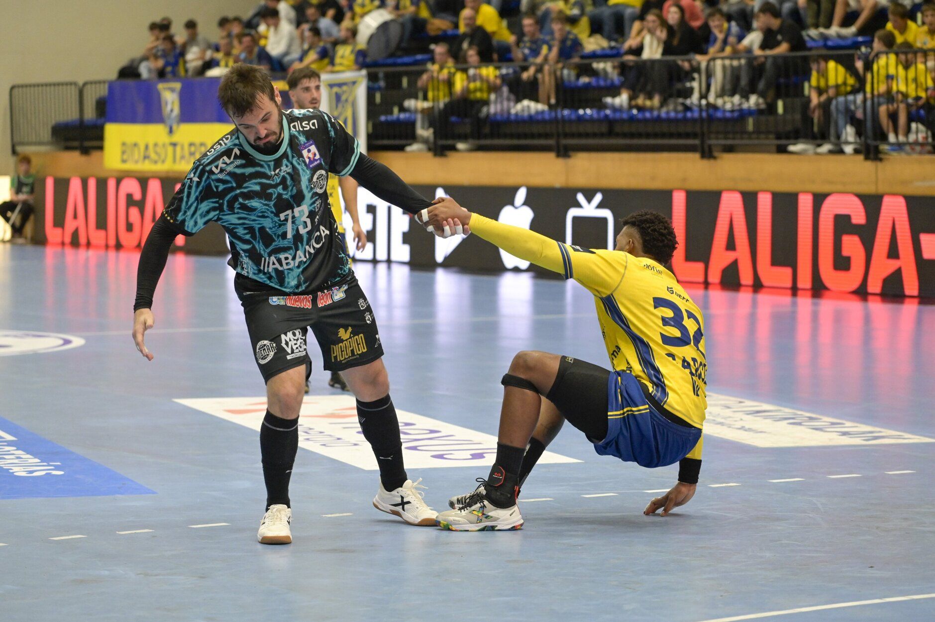 El jugador del Ademar Rodrigo Benites ayuda a levantarse al balonmanista del Irudek Bidasoa Irun Dariel García