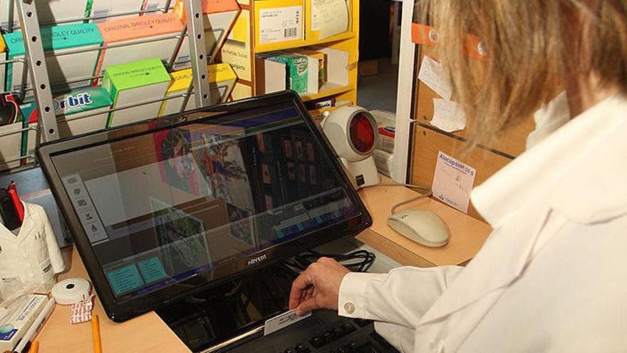 Una farmacéutica utiliza el nuevo sistema de lectura de la tarjeta sanitaria con el sistema informático.