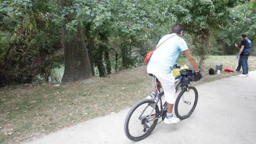 Un hombre circula en una bicicleta junto al río Arga.