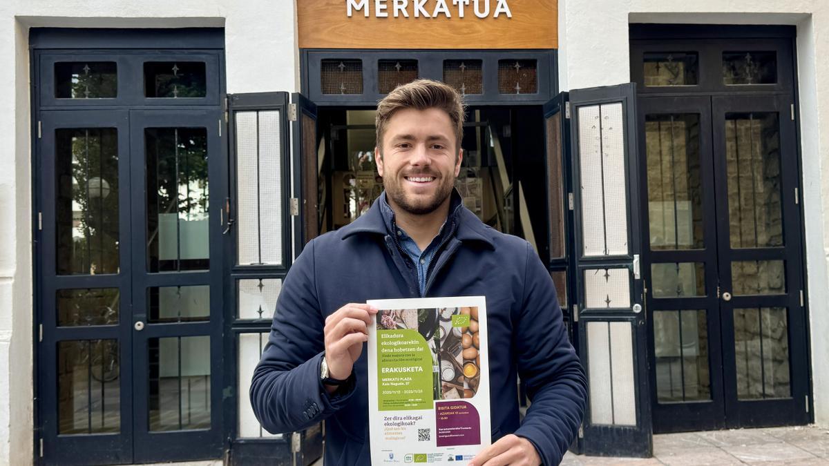Inaxio Illarramendi con el cartel de la exposición itinerante, fuera del mercado de Zarautz.