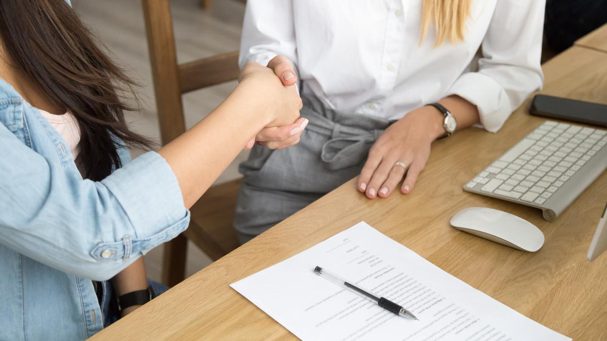 Una mujer estrecha la mano después de firmar su renuncia.