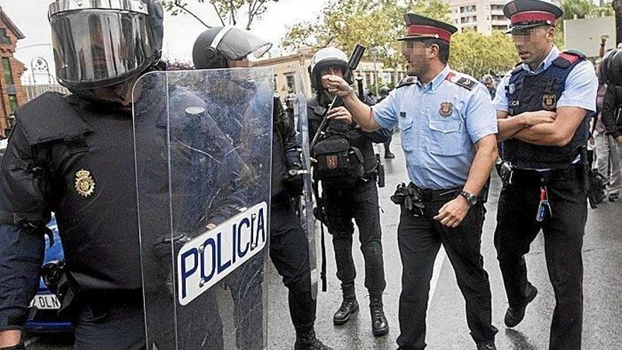 Un mosso se dirige a un policía nacional antidisturbios en L’Hospitalet de Llobregat.
