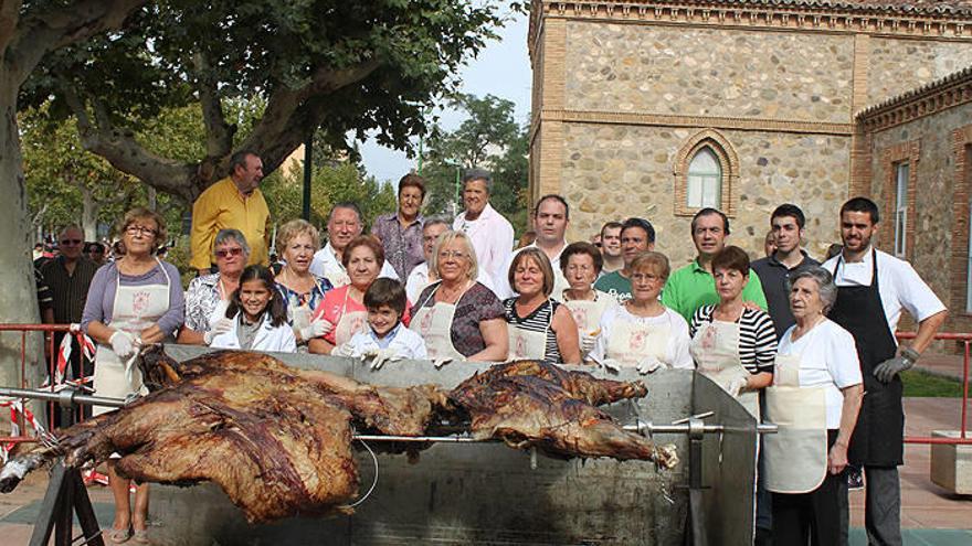 Voluntarios y vecinos posan con la ternera ya asada.